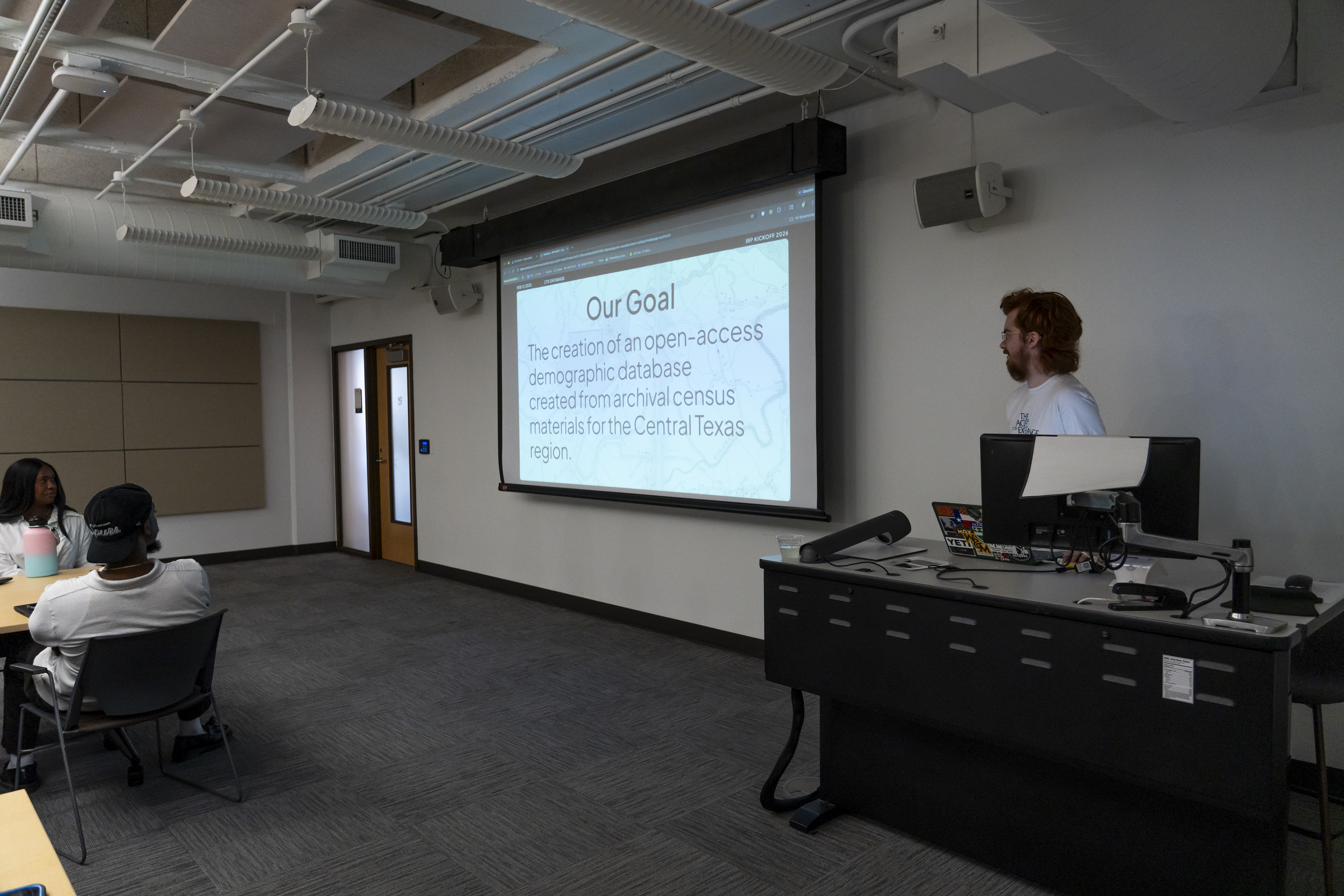 Presenting the 'Our Goal' slide in a lecture room at the IRP Kickoff